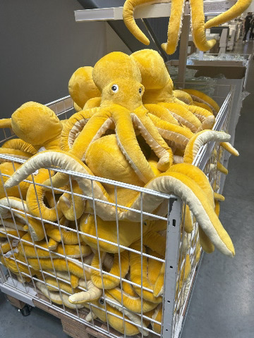 Image of dozens yellow squid plushies in a box.